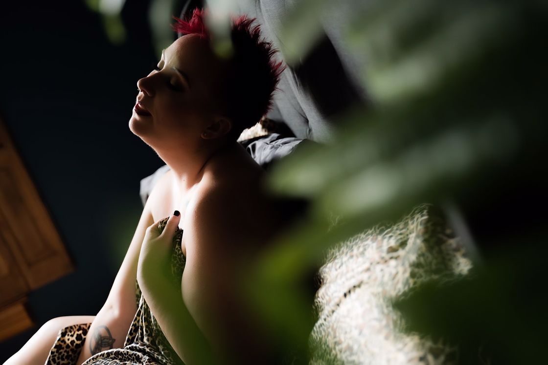 Woman wrapping herself with an animal print cloth while posing for her boudoir shoot in a bed