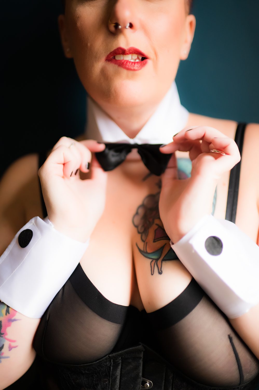 Close up of woman in black lingerie and bowtie biting her lip.