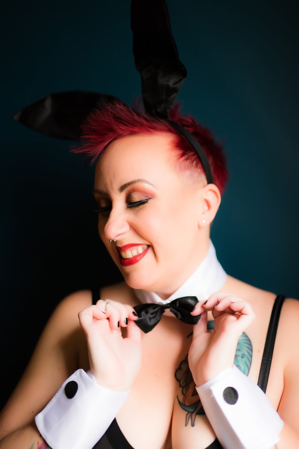 Playful boudoir photo of a woman in a playboy bunny costume pulling at her bowtie.