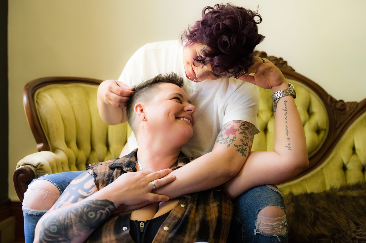 Person sitting on the floor while her partner caresses her hair during their boudoir shoot