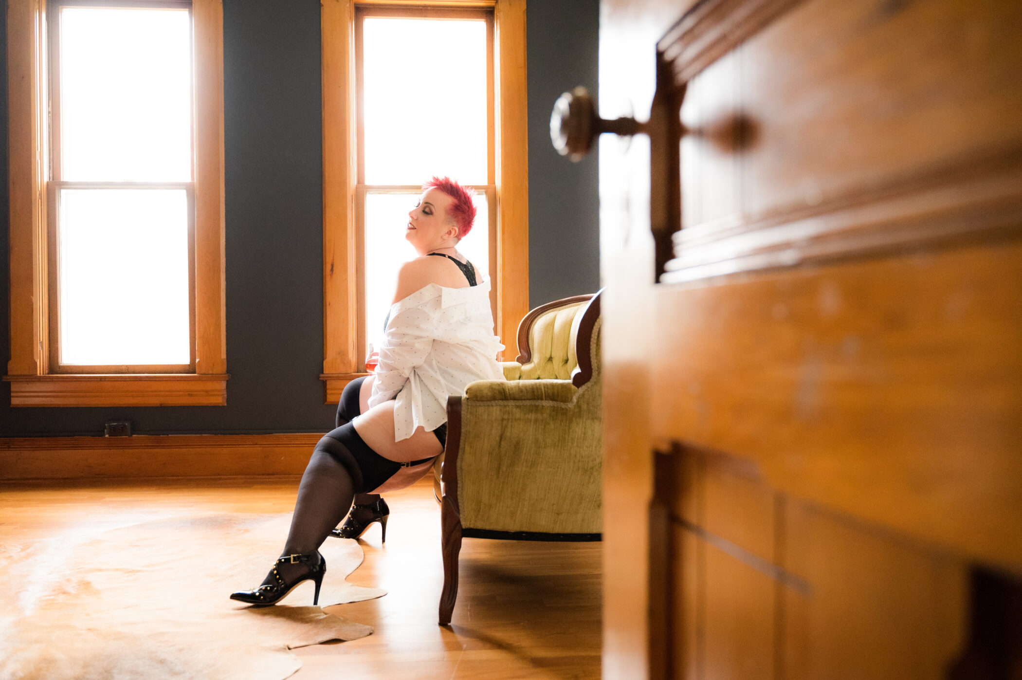 A woman sitting on a couch and posing for a boudoir photoshoot