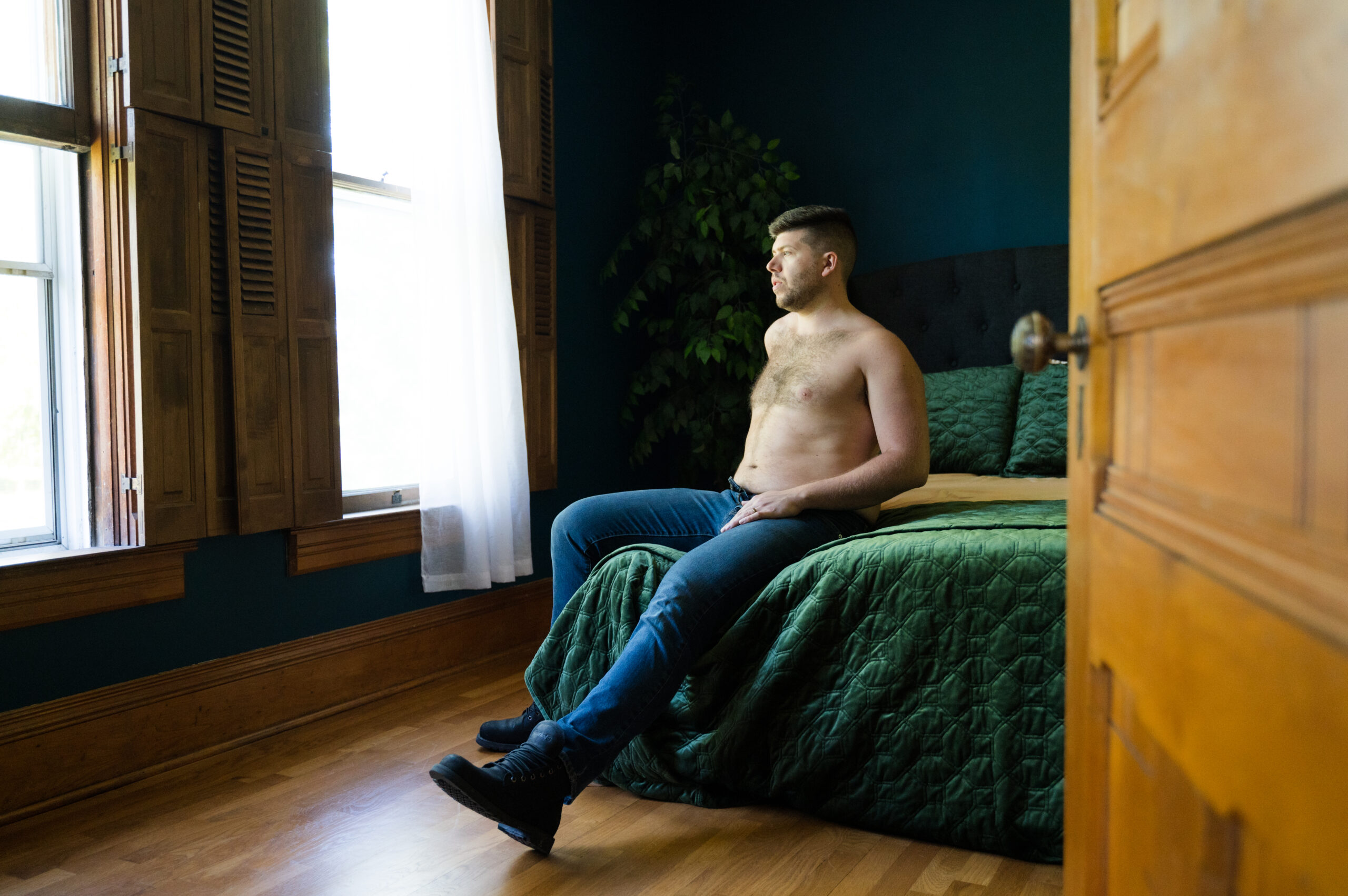A man posing on a bed for his boudoir photoshoot