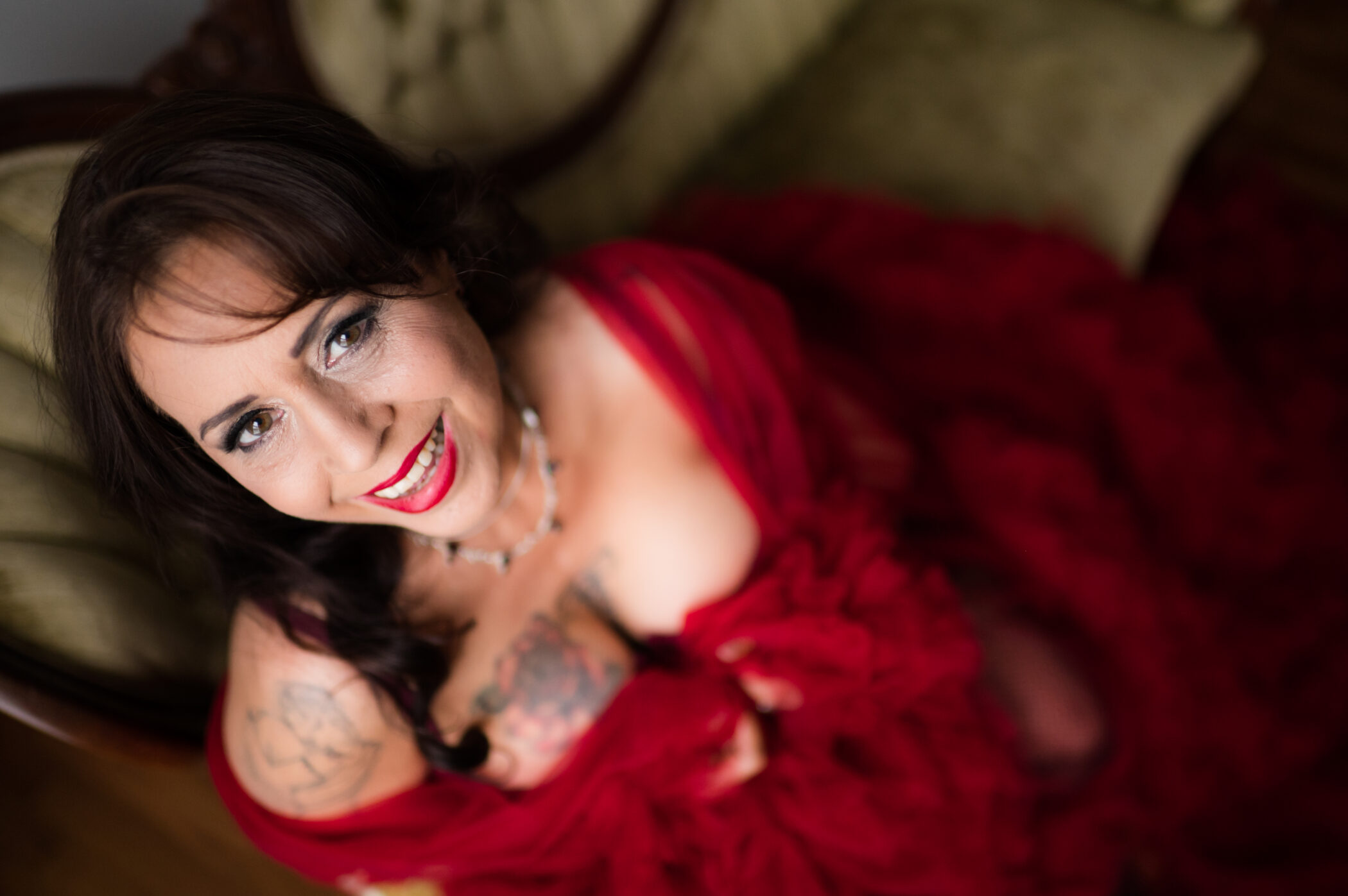A woman wearing a charming red dress looking at the camera for her boudoir photoshoot