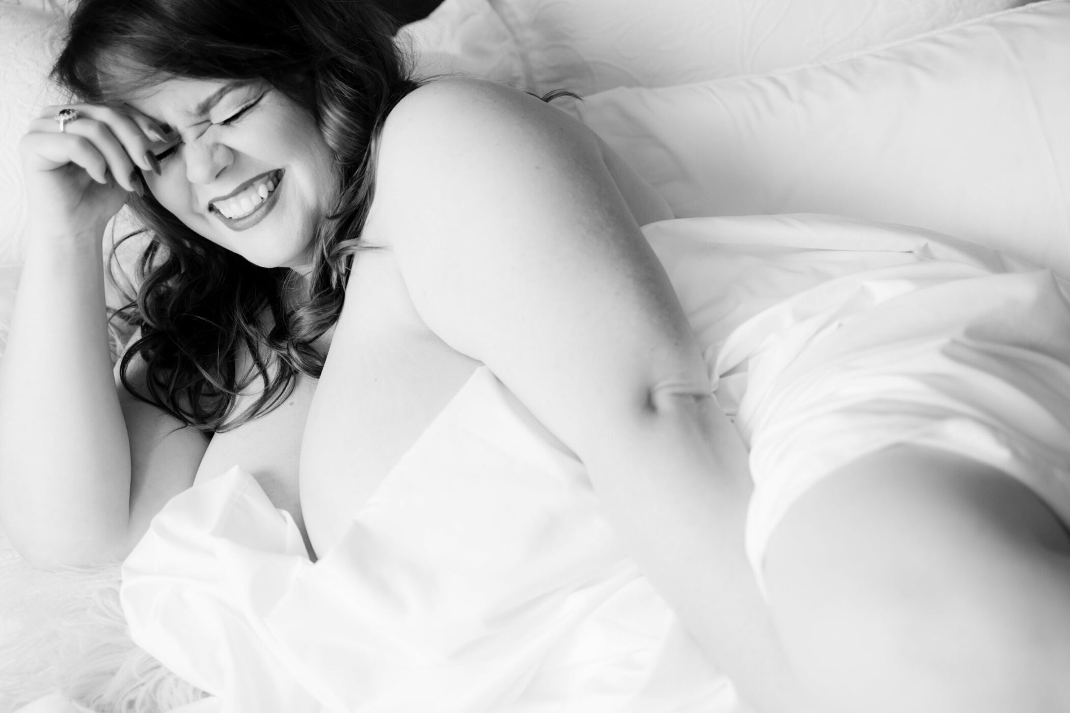 Energetic boudoir photo of woman smiling with her eyes closed during transformational boudoir session with Betsy McCue Pictures.