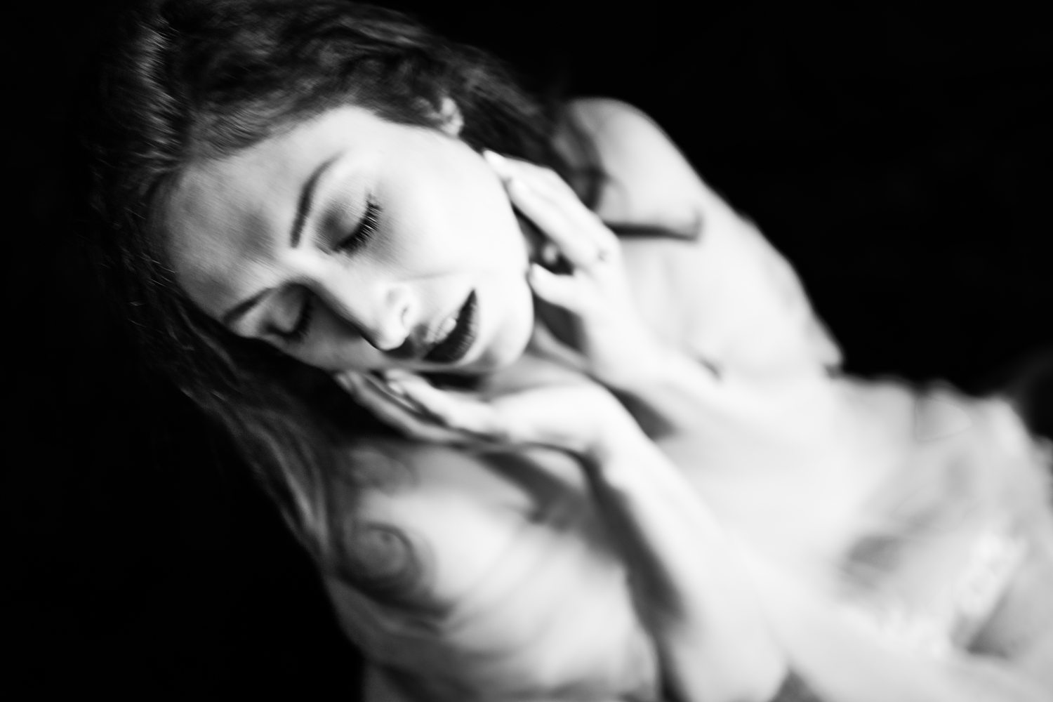 Boudoir portrait of woman holding her face in her hands during artistic boudoir session in Kalamazoo.