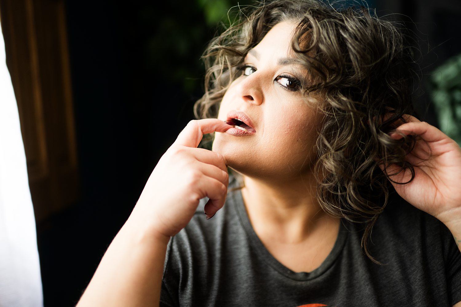 Sexy close-up portrait of woman playing with her hair while biting her finger during confidence building boudoir session.