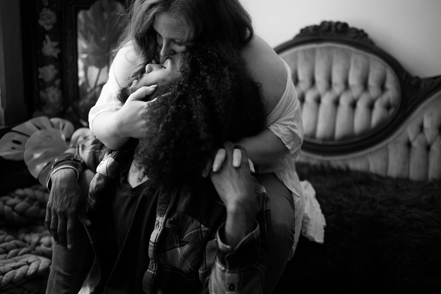 Classic black-and-white photo of a couple lovingly embracing sitting on an antique couch.