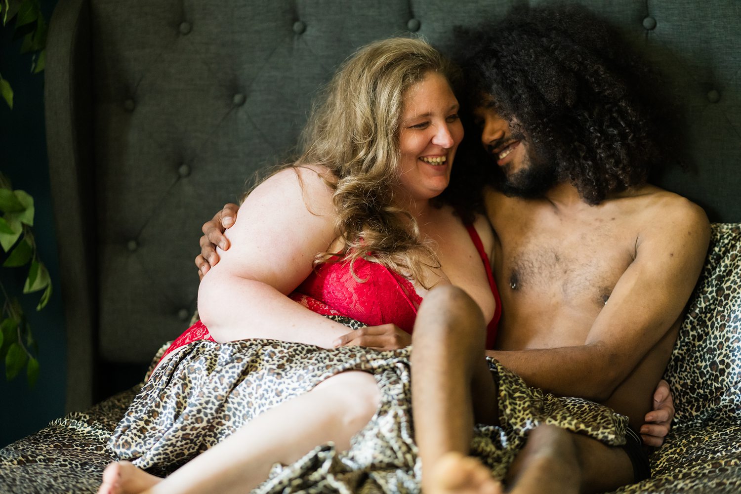 Intimate boudoir portrait of woman in red lingerie smiling lovingly at her boyfriend.