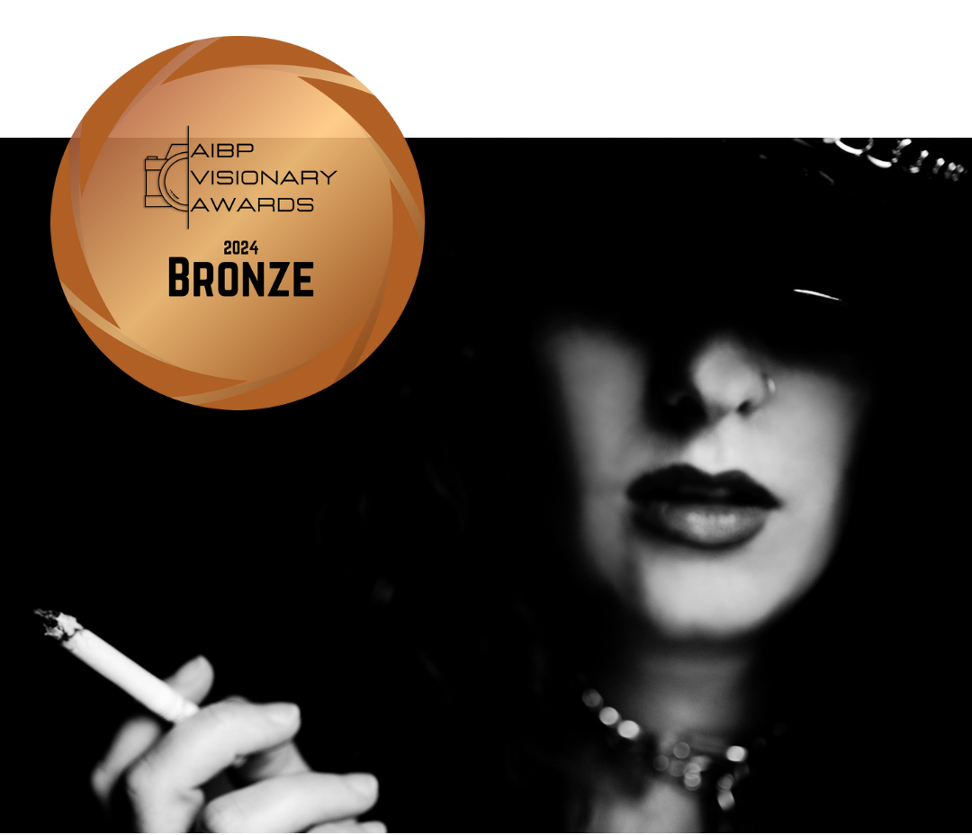 Artistic black-and-white portrait of woman holding a lit cigarette, AIBP Visionary Award winning photo.