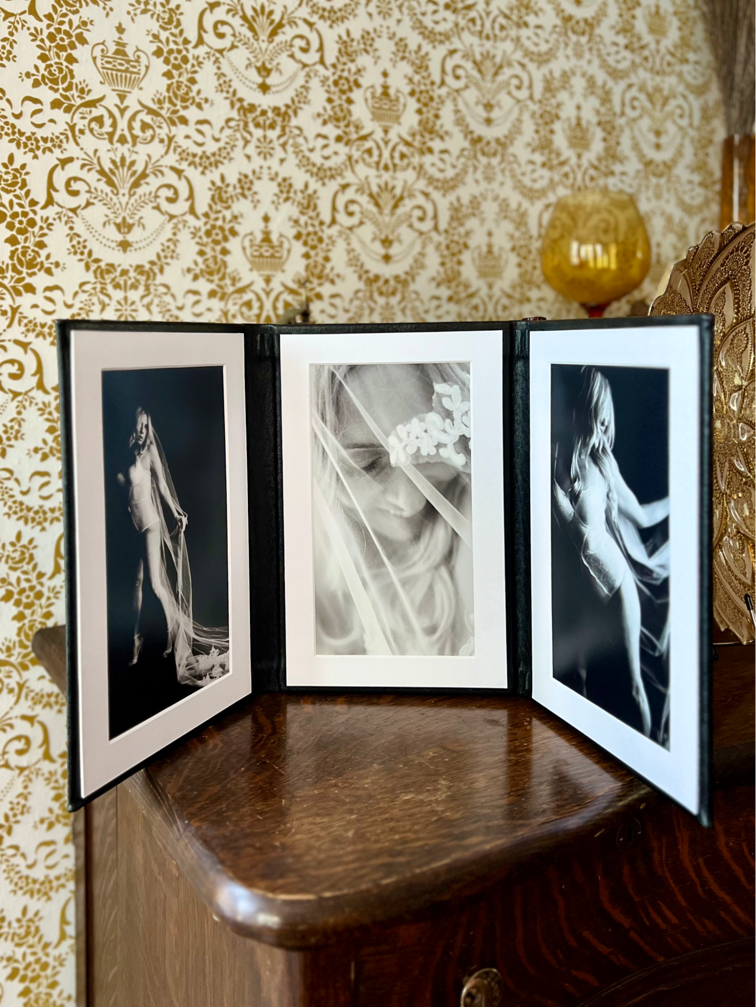 Luxury boudoir folio displayed on an antique buffet, showing high-quality photo prints.