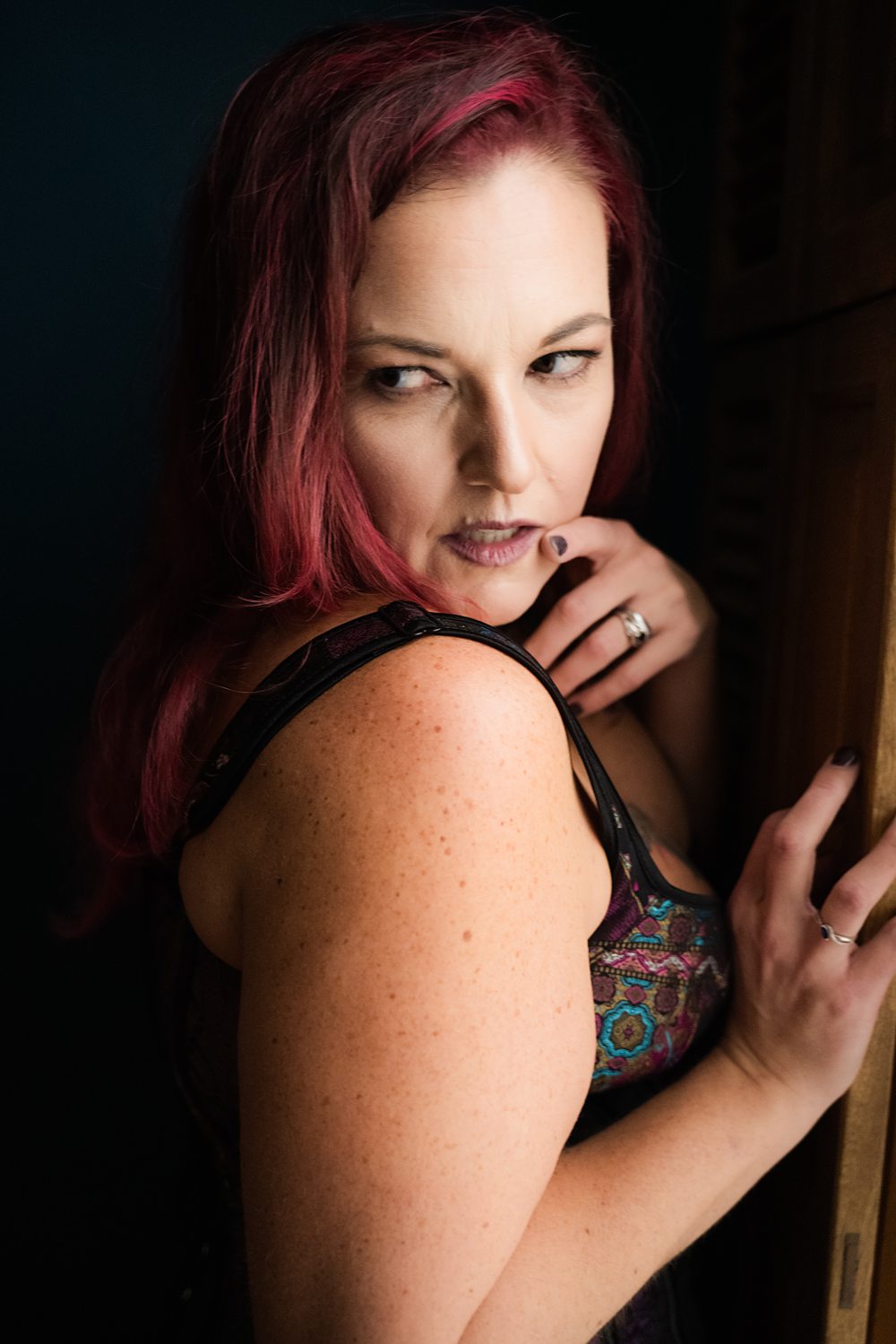 Boudoir photo of woman leaning against wall looking slyly away from the camera during soulful boudoir session in Kalamazoo.