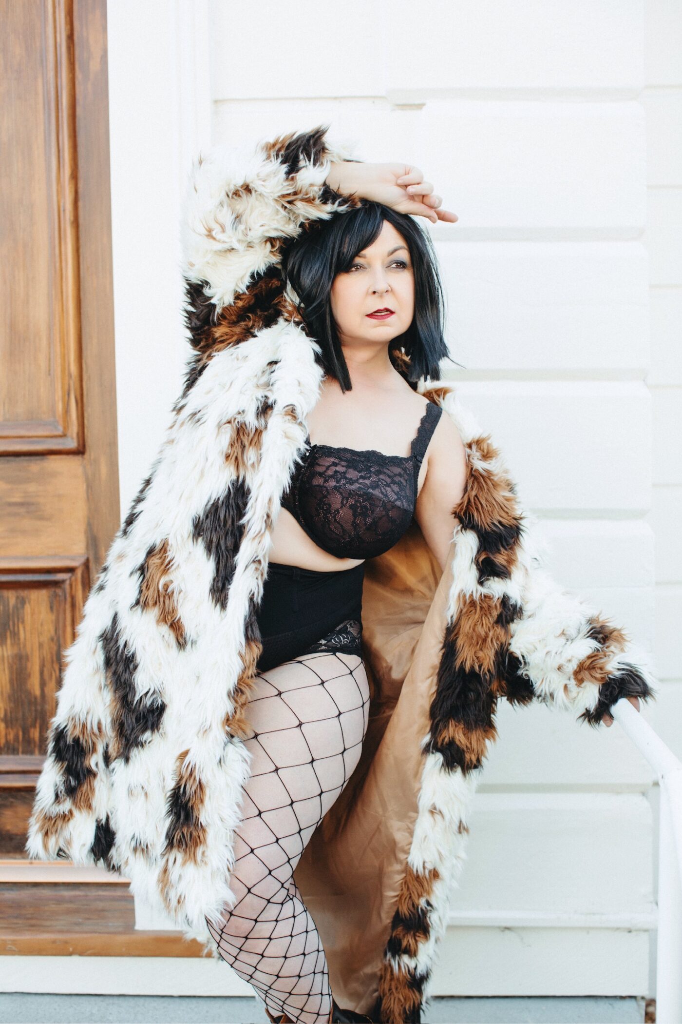 Betsy McCue Gibson, award-winning international intimate boudoir photographer in Kalamazoo Michigan, standing tall wearing black lingerie and fur coat.