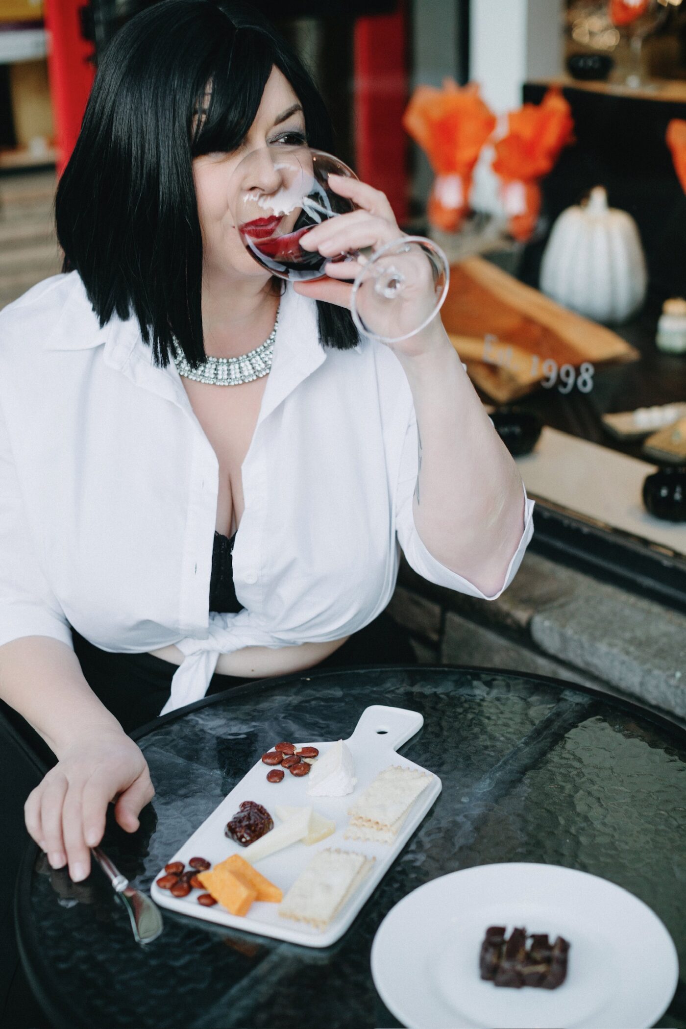 Betsy McCue Gibson, award-wining international boudoir photographer in Kalamazoo Michigan, seated at bistro table sipping red wine.