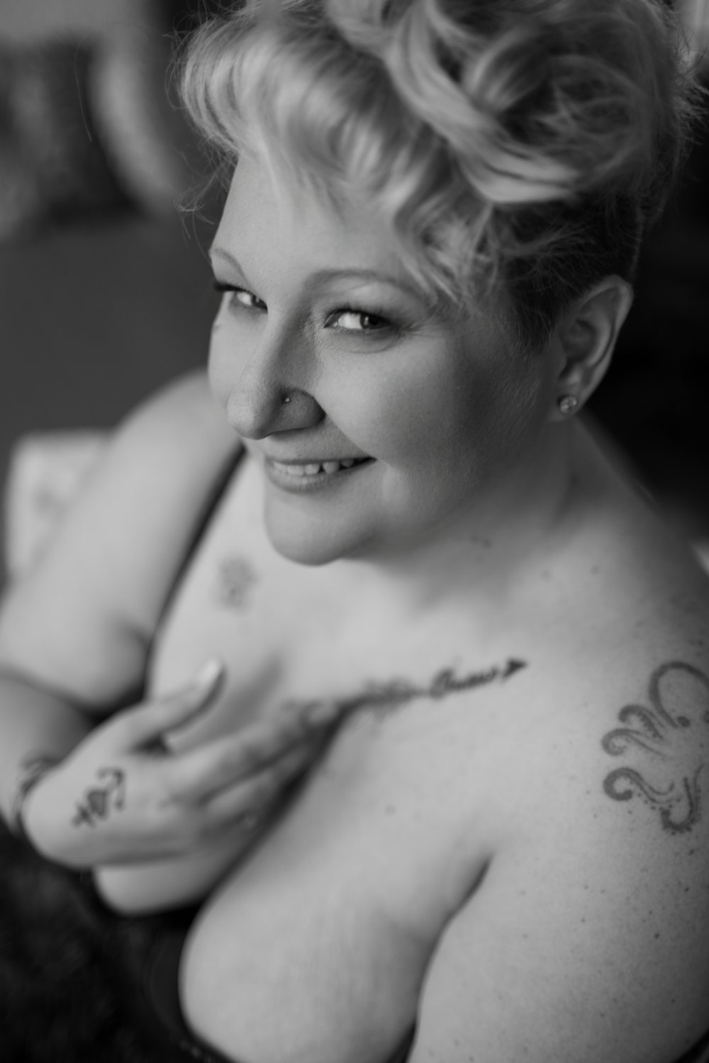 Emotive black and white photo of woman smiling touching her cleavage.