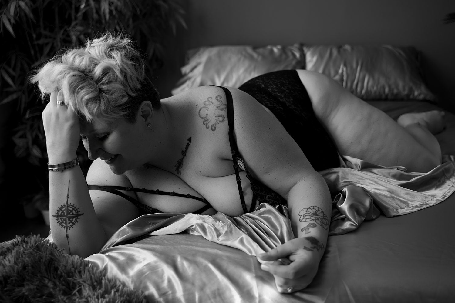Black-and-white photo of woman in-the-sheets wearing black lingerie.