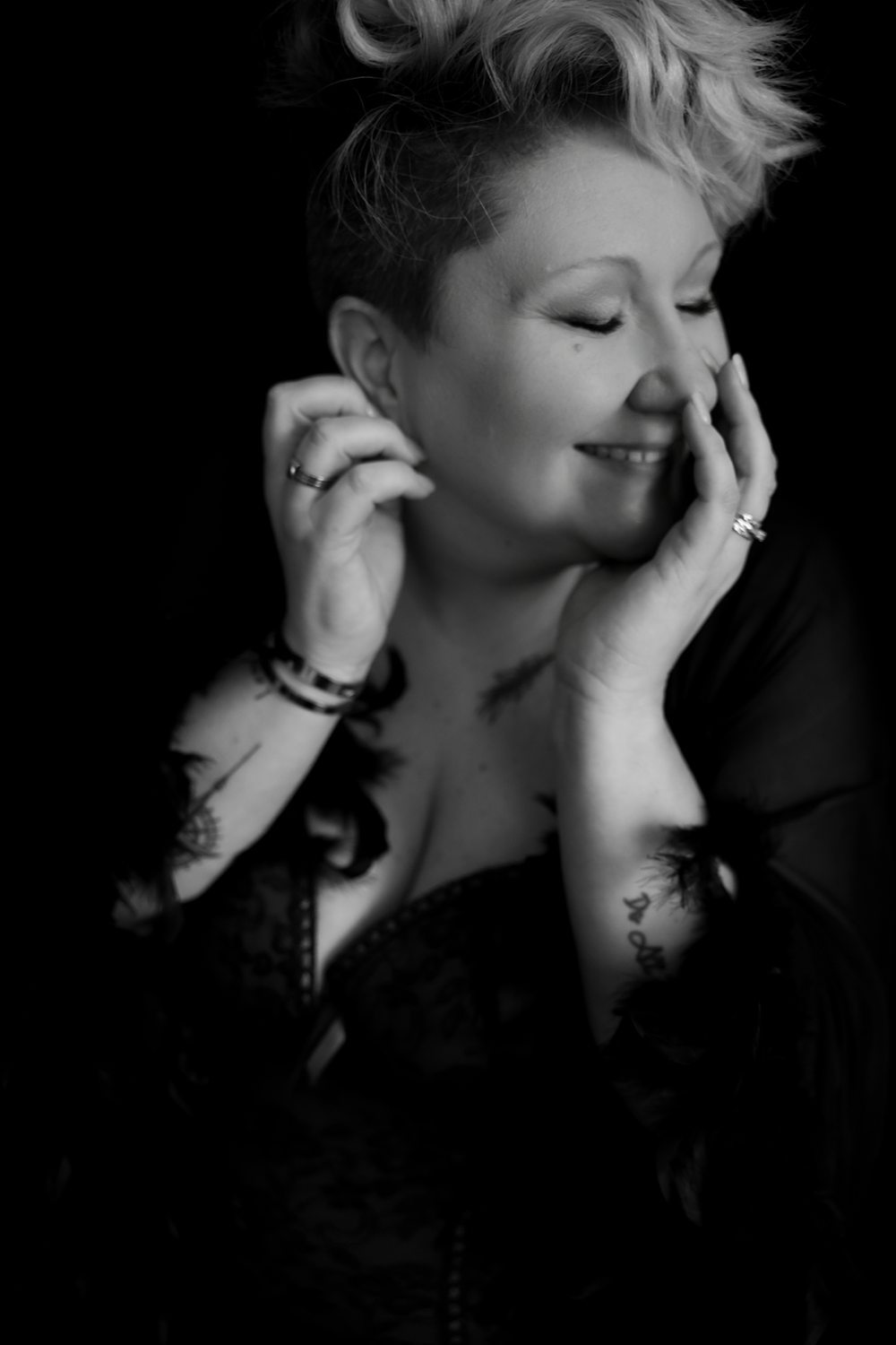 Playful black-and-white portrait of a woman smiling during a boudoir session at Betsy McCue Pictures.