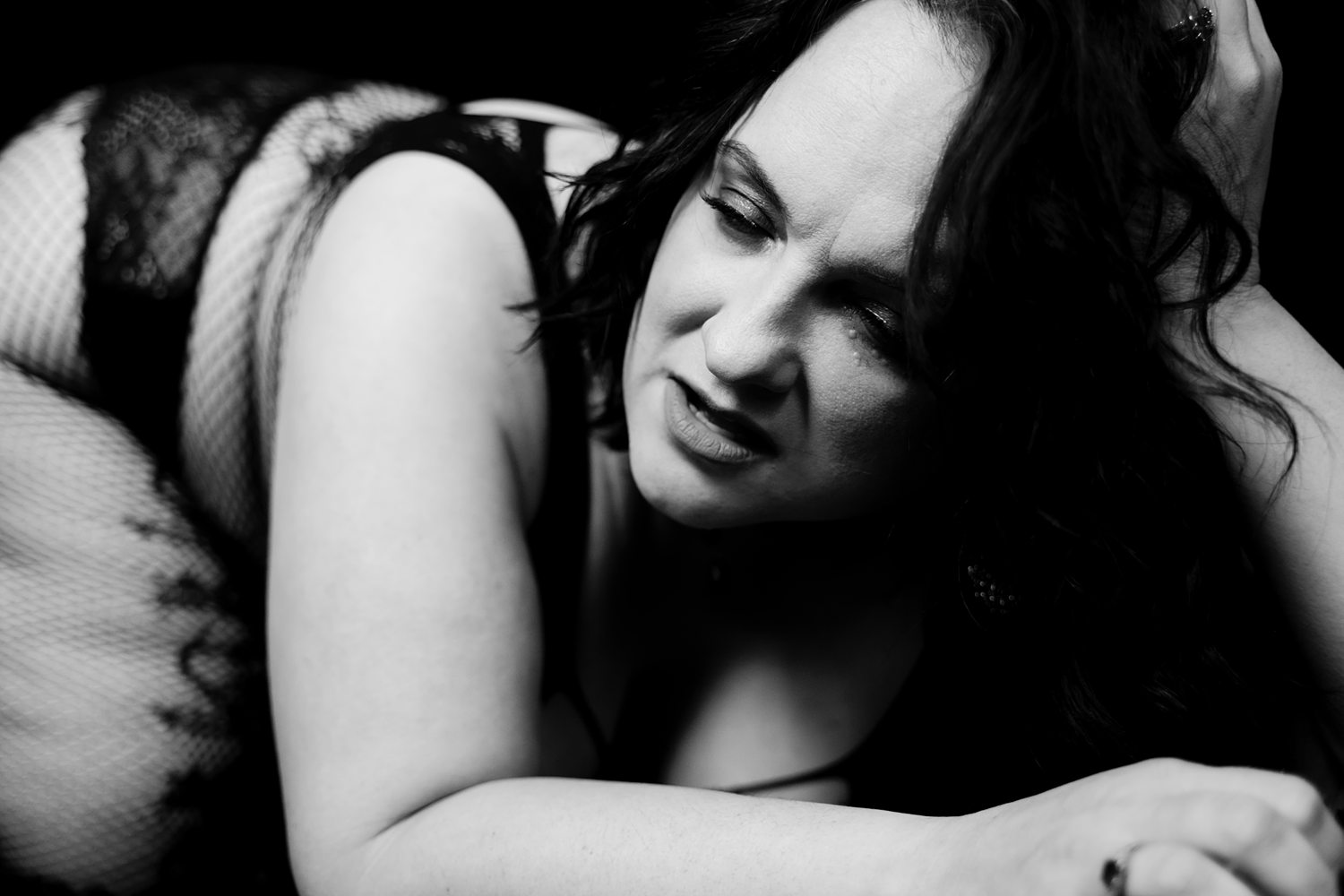 Black-and-white close up of woman in black lingerie and fishnets.