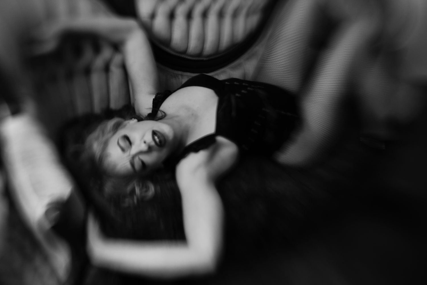 Artistic boudoir portrait of woman in her 40s reclined on a vintage sofa during empowering boudoir session in Kalamazoo.
