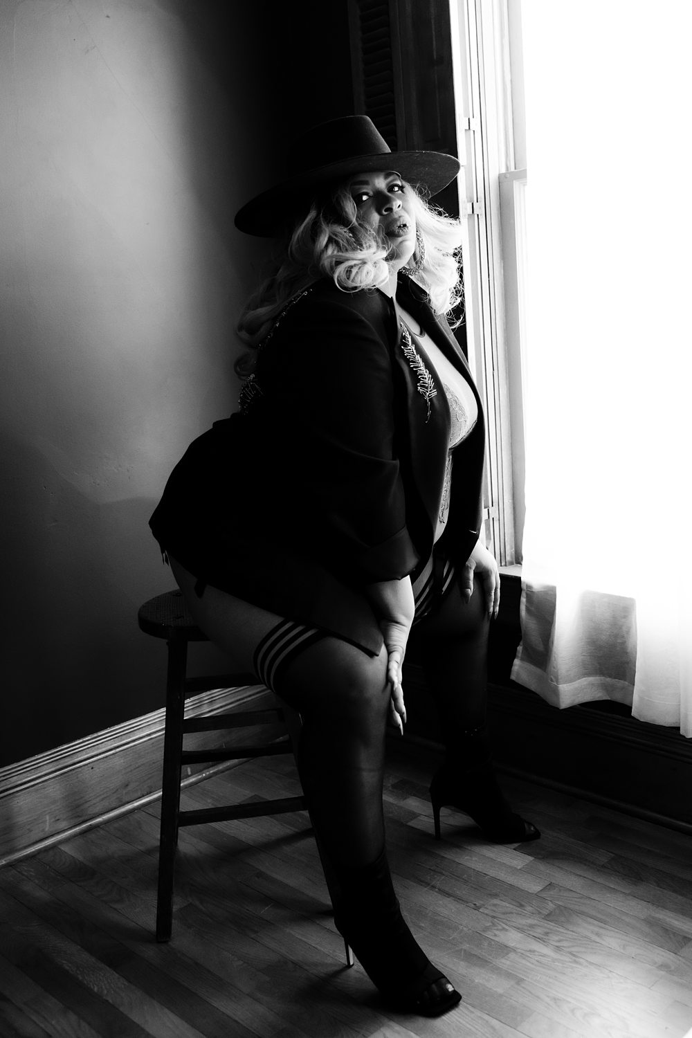 Black-and-white photo of woman wearing a suit jacket and hat confidently looking at the camera.