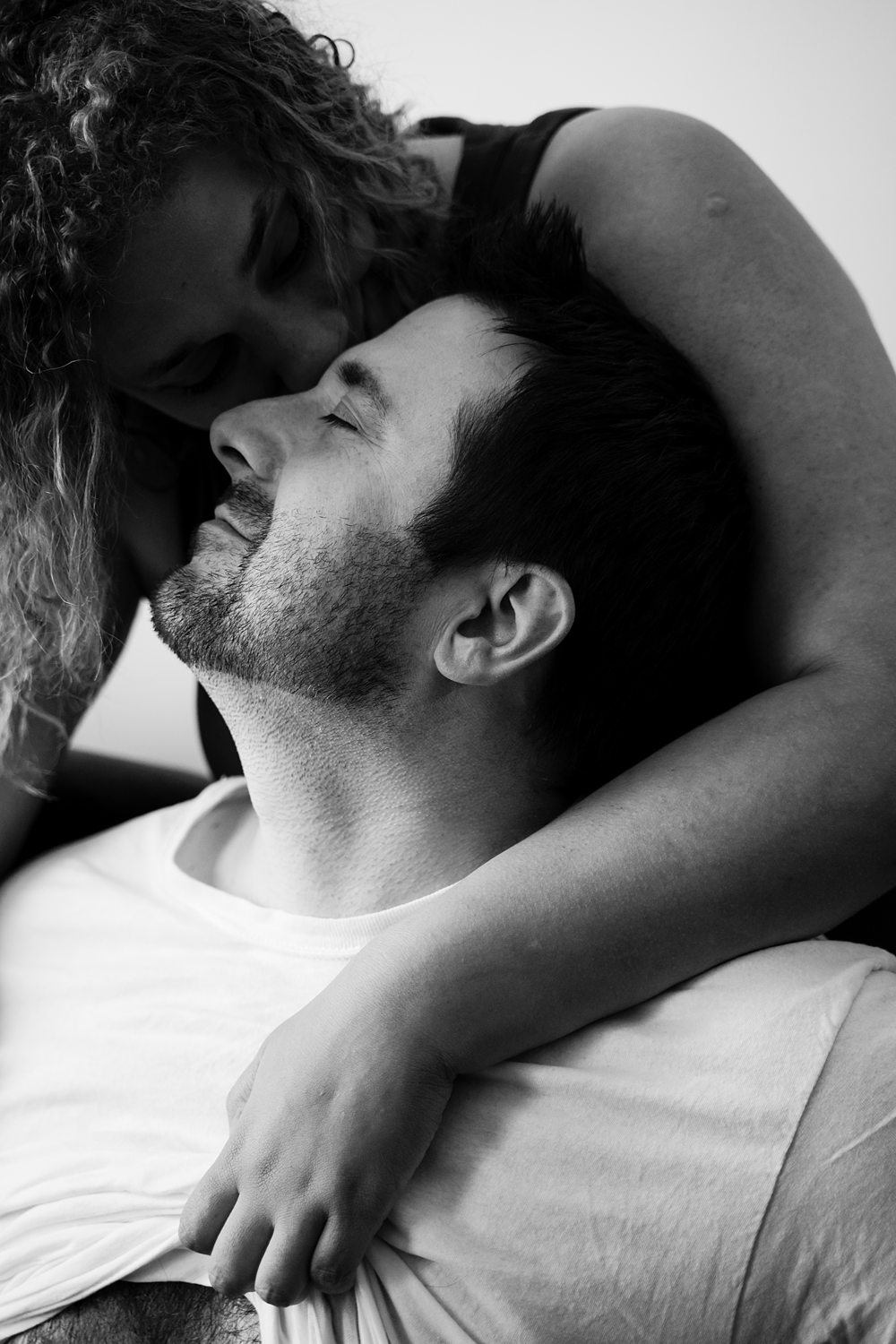 Intimate close up of woman caressing a smiling man, kissing him on the forehead.