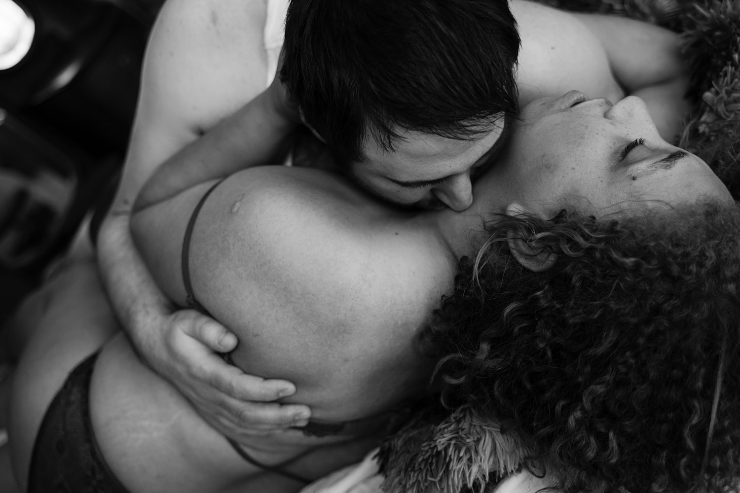 Sensual black-and-white photo of a man nuzzling a woman's neck during intimate couples session in Kalamazoo with Betsy McCue Pictures.