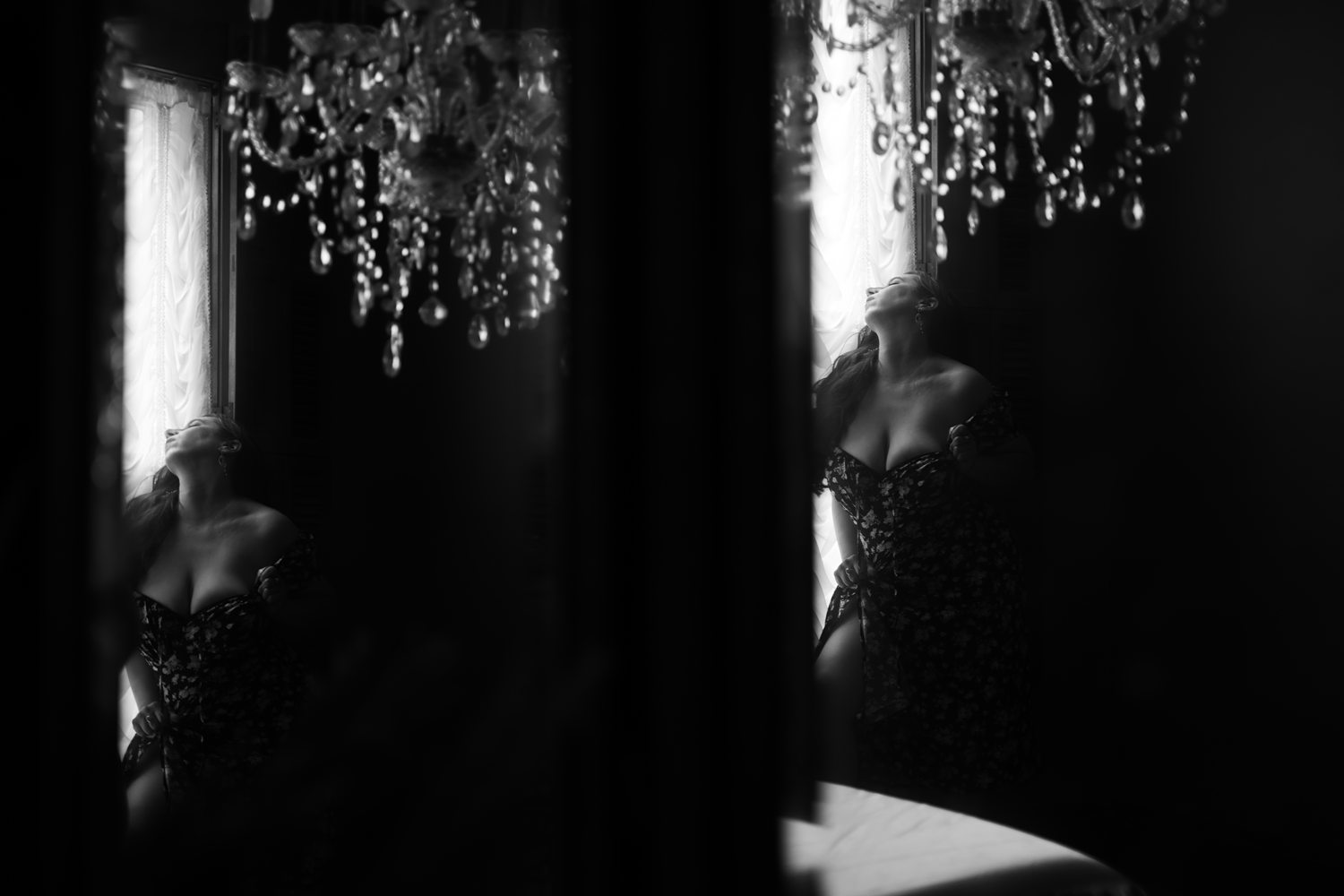 Vintage inspired black-and-white photo of woman looking out of the window during artistic boudoir session in Kalamazoo.